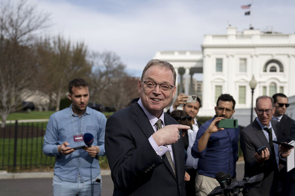 White House economic adviser Kevin Hassett stands with the White House behind him, speaking to members of the press.